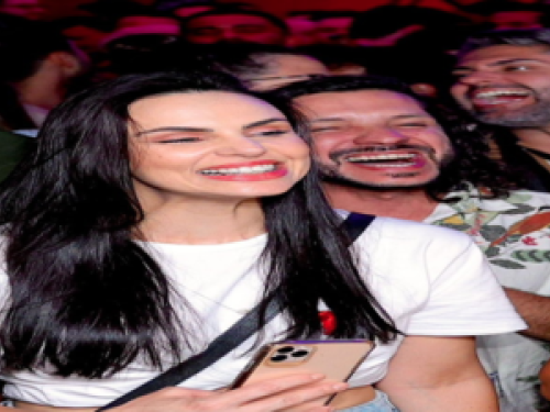 Imagem real de uma moça com o celular na mão sorrindo 