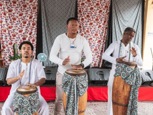 Homens em trajes umbandistas tocando atabaque