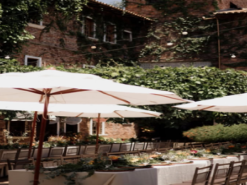 Imagem de uma mesa grande cheia de cadeiras e guarda sol 