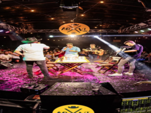 Imagem de um palco com um homem cantando para muitas pessoas 