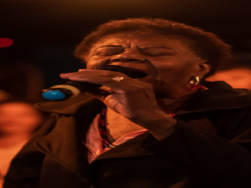 Imagem de uma mulher cantando no microfone 