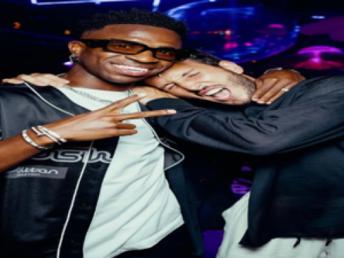 Imagem do jogador Vini jr posando para foto junto de um homem o abraçando 