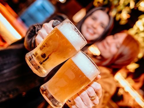 Imagem de duas mulheres segurando o copo de cerveja 