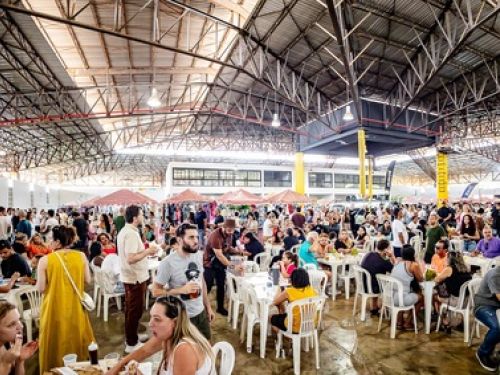 Imagem quadra do Mercado de Origem do Santa Tereza, com pessoas ocupando o espaço, barracas, mesas e cadeiras.
