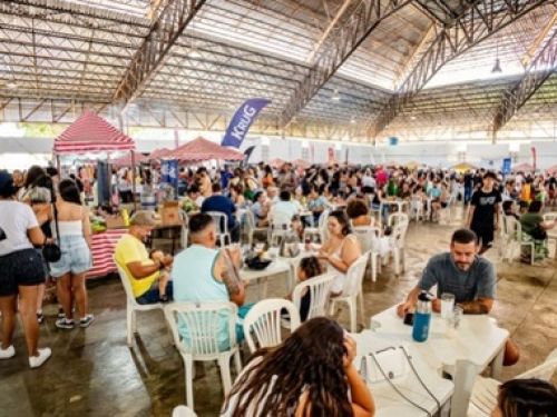 Imagem quadra do Mercado de Origem do Santa Tereza, com pessoas ocupando o espaço, barracas, mesas e cadeiras.