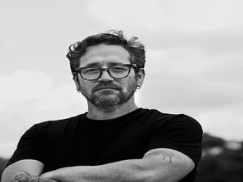 Imagem real de um homem de óculos e braços cruzados 