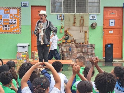 um homem cantando historias para muitas crianças