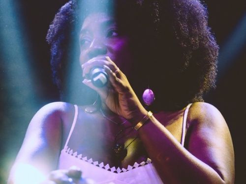 Fotografia da cantora Adriana Araújo com microfone ao palco