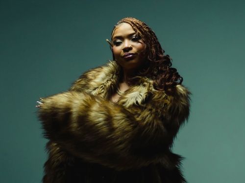 Imagem de um mulher de braços cruzados, usando um casaco de pelos. 