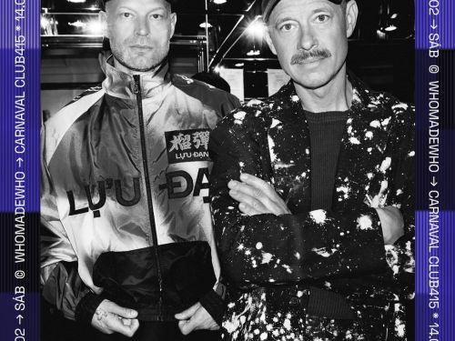 Imagem preta e branca, com dois homens em pé, usando boné, e uma jaqueta com vários desenhos 