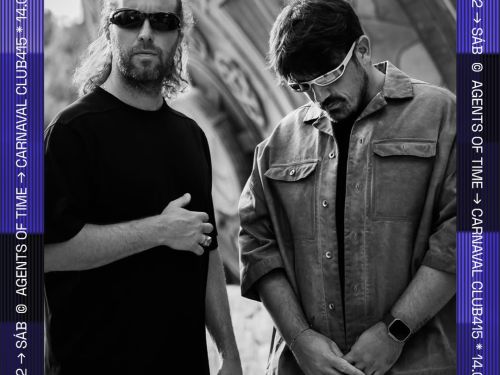 Imagem preta e branca, com dois homens usando óculos, um de blusa preta e outro com uma jaqueta jeans 