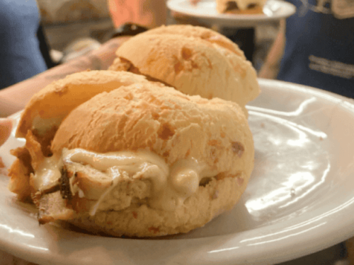 Foto de divulgação do evento "Minas é Muitas - experiência gastronômica nos Mercados de BH": Fotografia de três pães de queijo recheados com pernil desfiado e requeijão