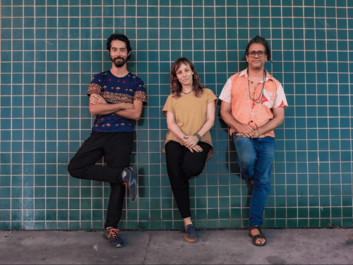 Imagem de três pessoas encostadas na parede.