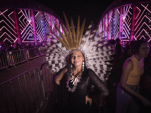 Imagem de uma mulher indígena, com um cocar e colares. 