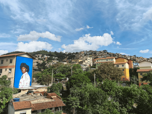 Imagem de um morro, com uma arte de uma mulher exposta em uma casa.