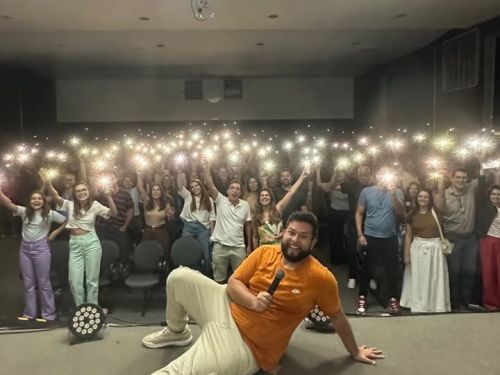Imagem do comediante sentando em cima do palco