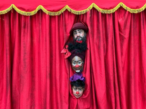 Foto divulgação mostra 3 artistas palhaços ciscenses atras das cortinas vermelhas de circo