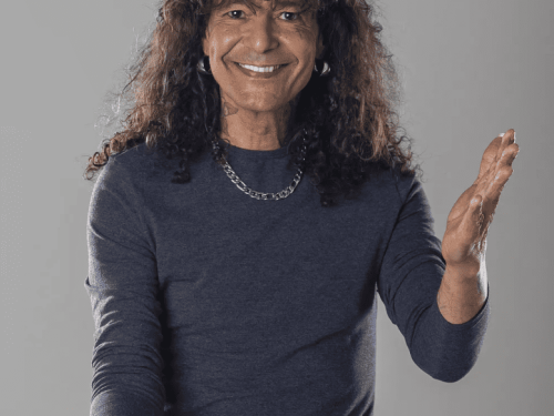 Imagem do cantor Luiz Caldas, com os cabelos soltos e sorrindo 