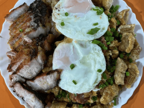 Um prato branco de bordas onduladas visto de cima, servido sobre uma mesa de cor laranja.