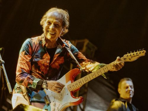 Imagem de Beto Guedes segurando uma Guitarra sorrindo 