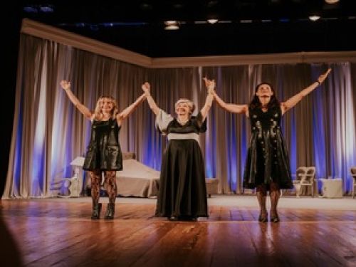 Imagem das três atrizes levantando as mãos se despedindo do público 