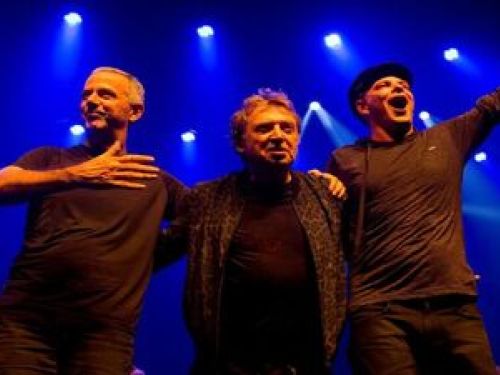 Imagem dos três integrantes da banda se abraçando 