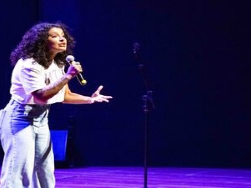 Imagem de Giovana segurando um microfone em cima do palco 