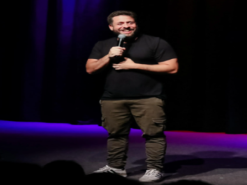 Imagem de maurício sorrindo com um microfone na mão 