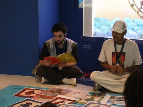 Dois rapazes sentados no chão enquanto conferem os materiais da oficina.