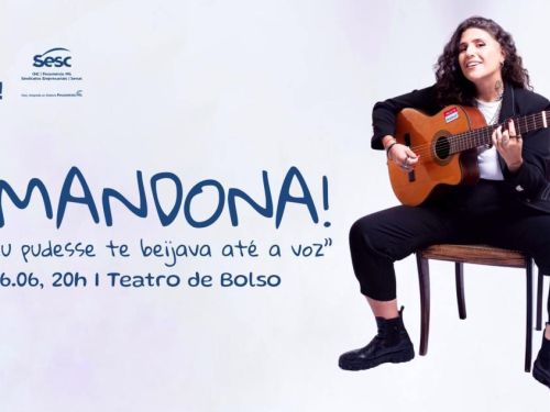 Artista Amandona. Mulher com cabelo cacheado está sentada em um banco, tocando violão e sorrindo.