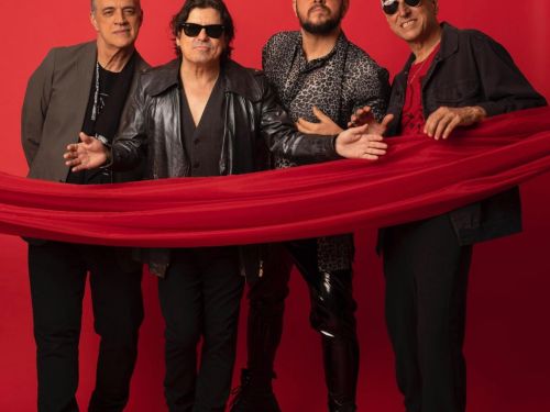 Fotografia promocional da atual formação da banda Barão Vermelho (Rodrigo Suricato, Fernando Magalhães, Guto Goffi e Maurício Barros) posando contra um fundo vermelho vibrante. Os quatro músicos estão de pé, vestidos com roupas pretas e estilosas, enquanto seguram e são atravessados por uma longa faixa de tecido vermelho que cruza horizontalmente a imagem.