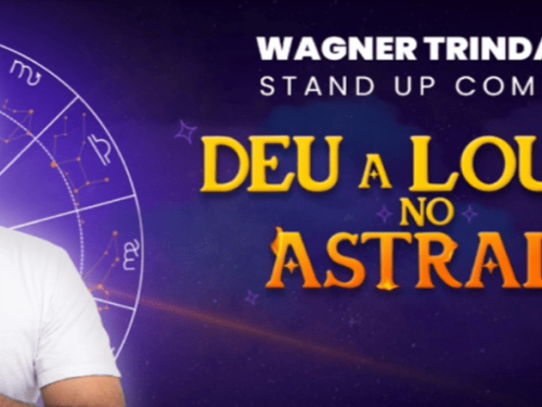 Banner promocional do show de stand-up de **Wagner Trindade**, intitulado **"Deu a Louca no Astral!"**. O humorista aparece à esquerda, sorridente e com as mãos postas em sinal de agradecimento, sobreposto a um fundo roxo com um mapa astral e constelações. O título do show ganha destaque à direita em letras amarelas e laranjas com brilhos, reforçando a temática mística e divertida da apresentação.