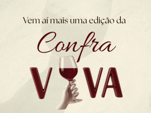 Card promocional em tom creme com o texto "Vem aí mais uma edição da Confra VIVA". O nome do evento destaca-se com "Confra" em letras cursivas e "VIVA" em letras grandes e tridimensionais na cor vinho, onde a letra "I" é criativamente substituída pela imagem de uma mão segurando uma taça de vinho tinto.
