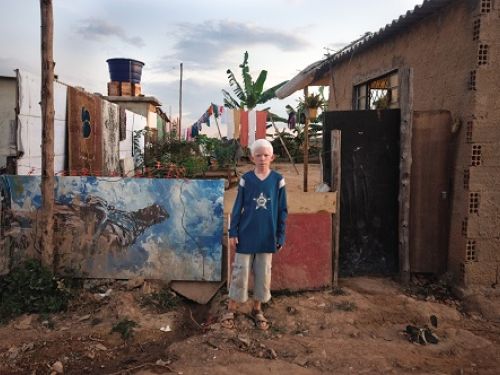 Fotografia de uma menino na frente da faixada da casa