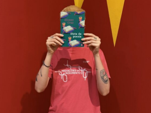 Foto de uma pessoa segurando um livro na frente do rosto 