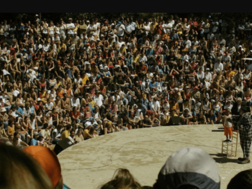 Imagem de edições anteriores do FIT BH, com uma apresentação de um palhaço num picadeiro e em volta o público sentado assistindo lotando a platéia.