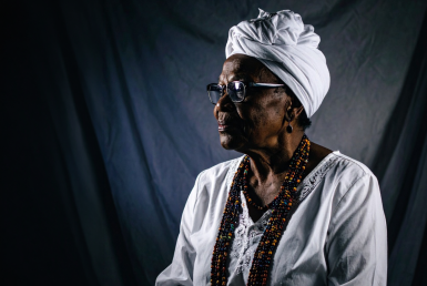 Imagem de uma mulher negra com vestes típicas brancas usadas em religiões de matriz africana.
