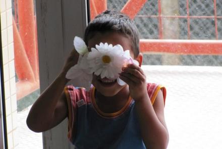 Criança segurando flores na frente de seus olhos 