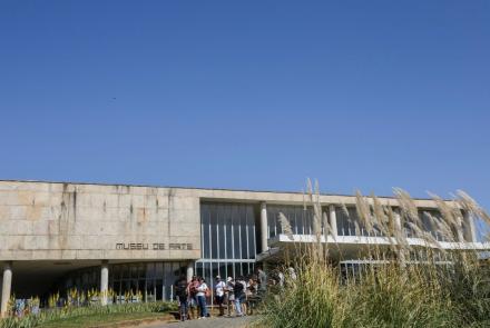 Fachada do Museu de Arte da Pampulha em um dia de sol, céu azul sem nuvens, algumas plantas do jardim na lateral direita