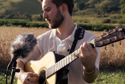 Imagem do cantor Rafael cantando com um violão