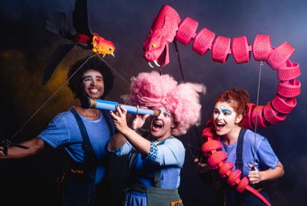 Três pessoas com roupas coloridas e portando brinquedos