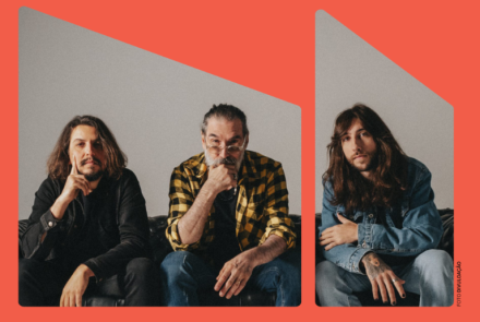 Imagem de três homens sentados em um sofá, com um fundo branco