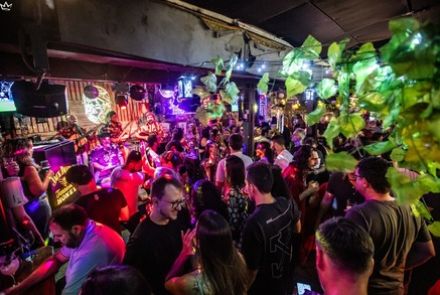 A foto mostra a pista do estabelecimento jangal, com letreiros luminosos nas paredes e pessoas ocupando o espaço 