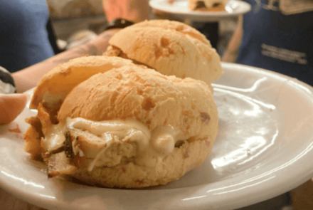 Foto de divulgação do evento "Minas é Muitas - experiência gastronômica nos Mercados de BH": Fotografia de três pães de queijo recheados com pernil desfiado e requeijão