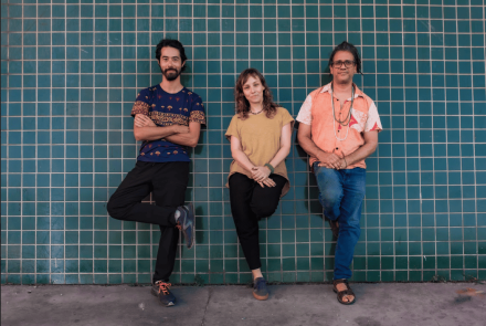 Imagem de três pessoas encostadas na parede 