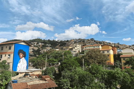 Imagem de um morro, com uma arte de uma mulher exposta em uma casa.