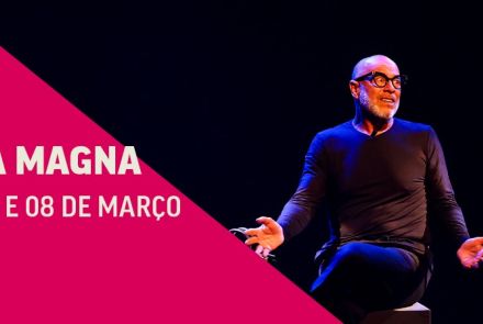 Folder de divulgação da apresentação artística "Hannah Arendt – Uma Aula Magna". À direita, homem sentado em um banco, usando blusa de manga longa e calça com cores escuras enquanto gesticula. Imagem dividida em fundo preto e rosa, com informações sobre o espetáculo – título e datas.