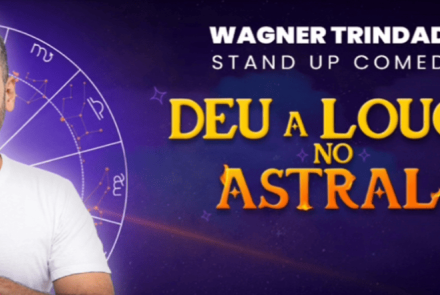Banner promocional do show de stand-up de **Wagner Trindade**, intitulado **"Deu a Louca no Astral!"**. O humorista aparece à esquerda, sorridente e com as mãos postas em sinal de agradecimento, sobreposto a um fundo roxo com um mapa astral e constelações. O título do show ganha destaque à direita em letras amarelas e laranjas com brilhos, reforçando a temática mística e divertida da apresentação.