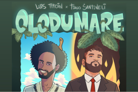 "LUÍS TITOIN x TIAGO SANTINELI" e o título "OLODUMARE" em letras grandes verde-água. A imagem é dividida ao meio: à esquerda, um homem negro sorridente com cabelo black power e colar de contas sob um fundo de céu azul; à direita, um homem branco de barba vestindo terno e gravata vermelha sob um fundo com chamas de fogo.