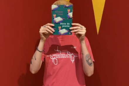 Foto de uma pessoa segurando um livro na frente do rosto 